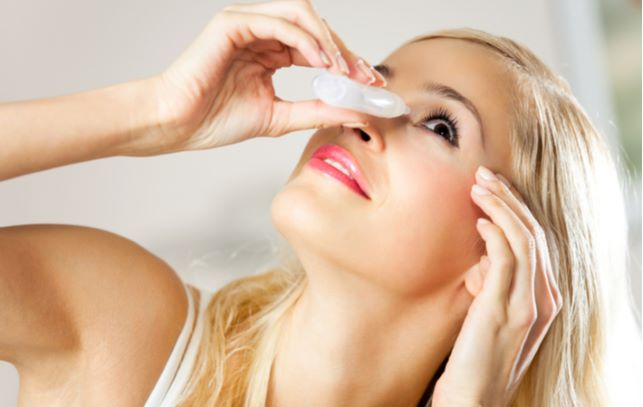 Women putting in eye drops for relief of dry eyes caused by contact lenses