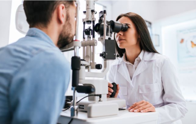 Young man undergoing eye exam by his optometrist at clinic