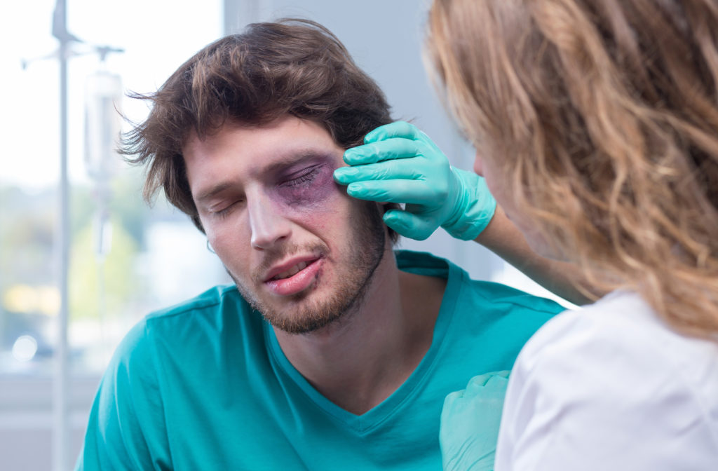 Man suffering from eye emergency and having eye checked by optometrist