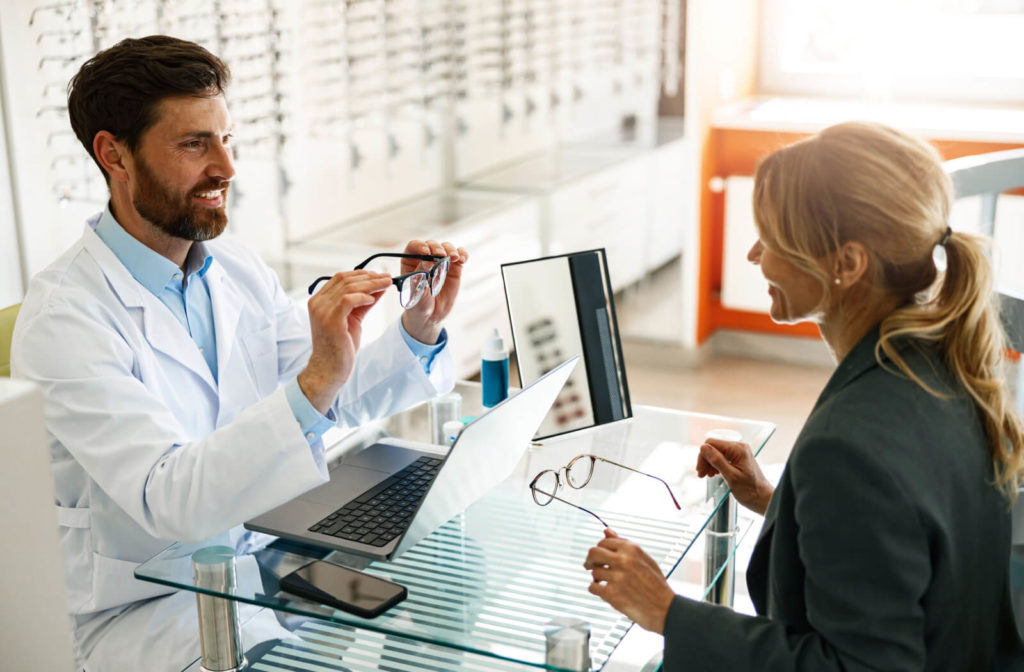 A woman getting help from a professional optician at the optical store while she is buying an eyeglass.