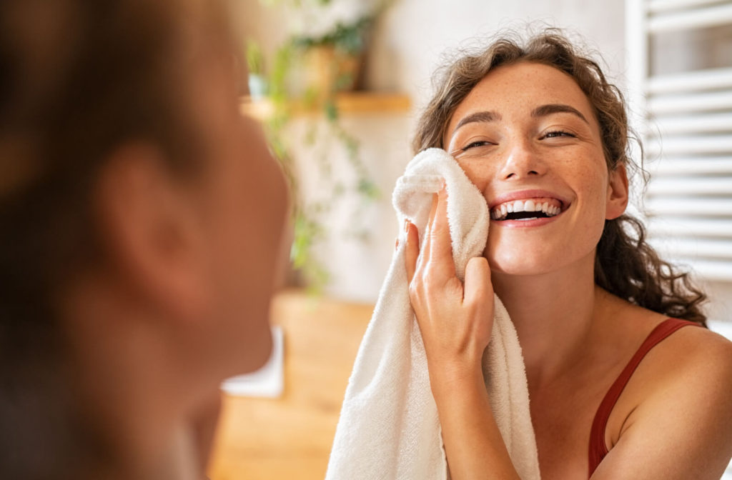 Young woman cleaning her face with a clean towel to prevent blepharitis