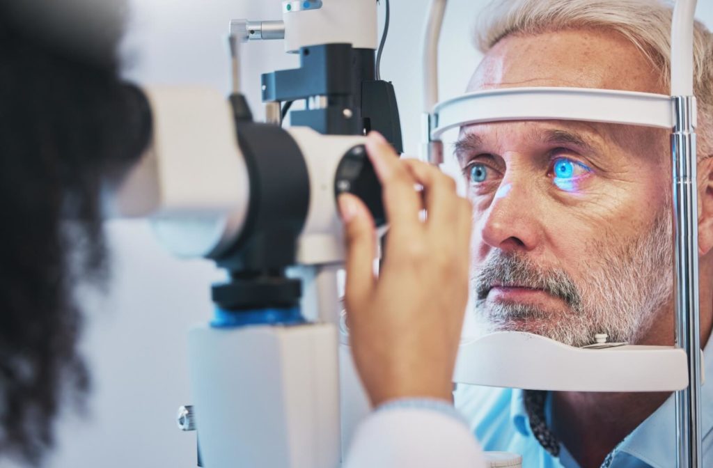 A senior man is going through slit lamp as he undergoes a annual eye exam with his optometrist using OHIP