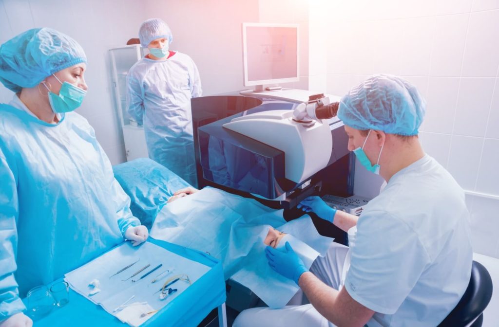 Surgical team performing LASIK eye surgery on patient using modern laser technology in a sterile operating room