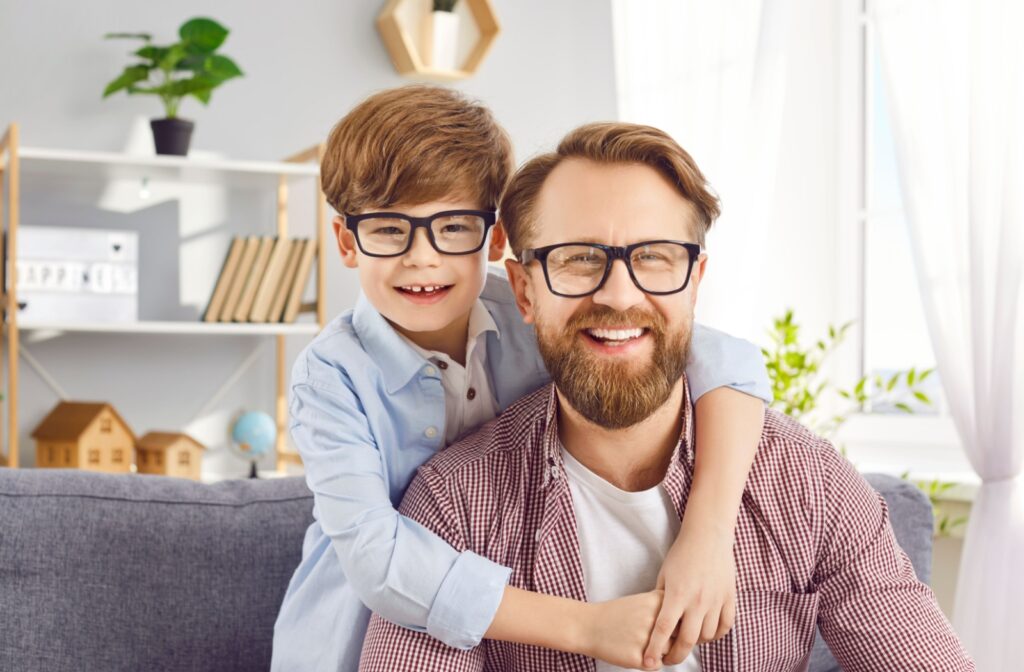 A smiling parent and their child showing off their matching eyeglasses.