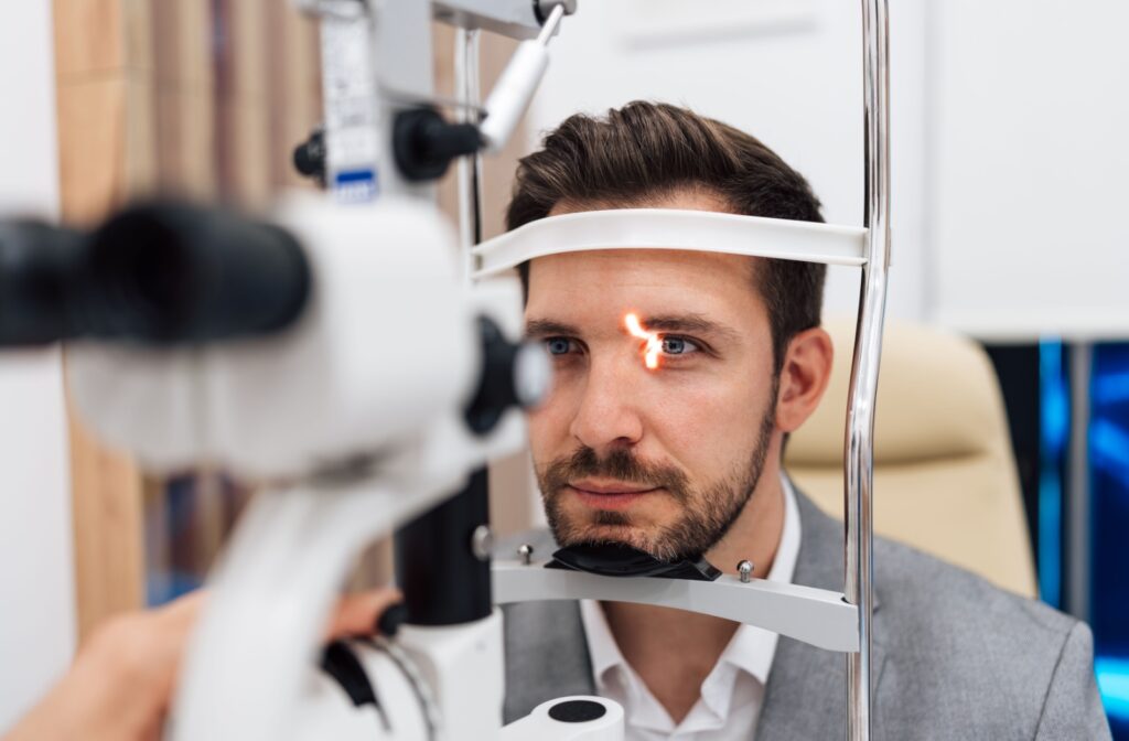 A person sitting in a chair undergoing a slit eye test during an eye exam