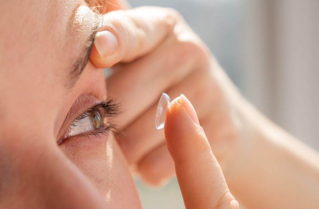 A close up of someone putting a contact lens into their eye