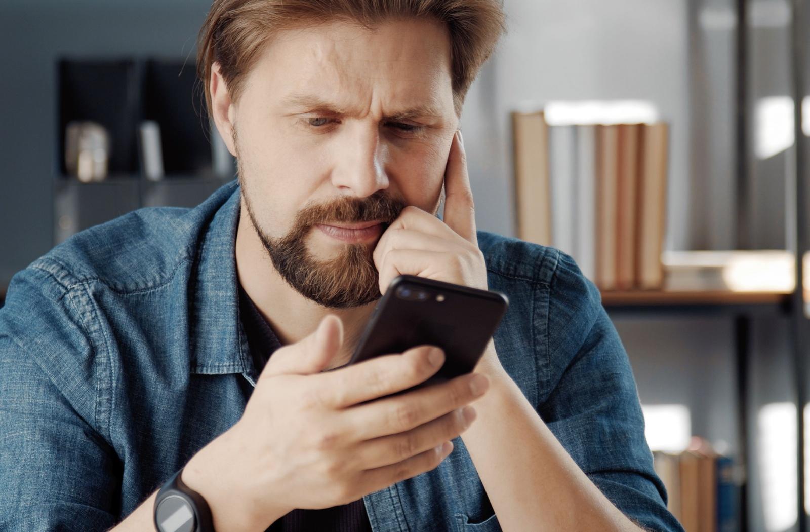 A person squinting while looking at their phone