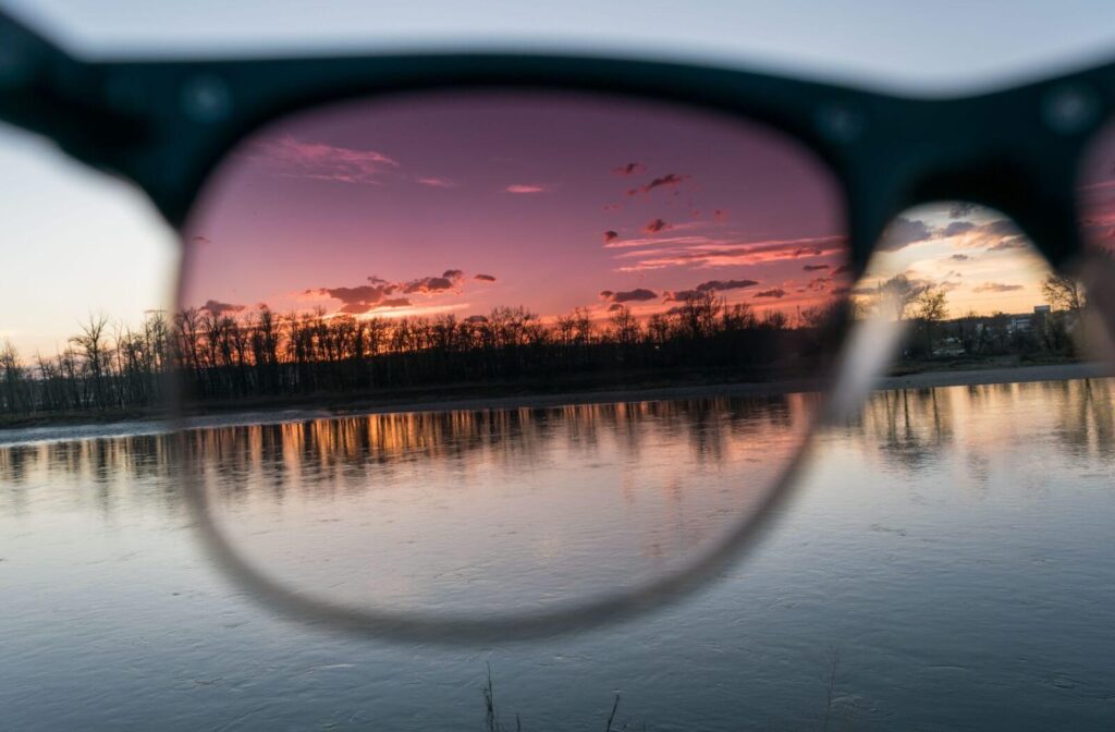 A pair of polarized sunglasses looking through the lens at a lake